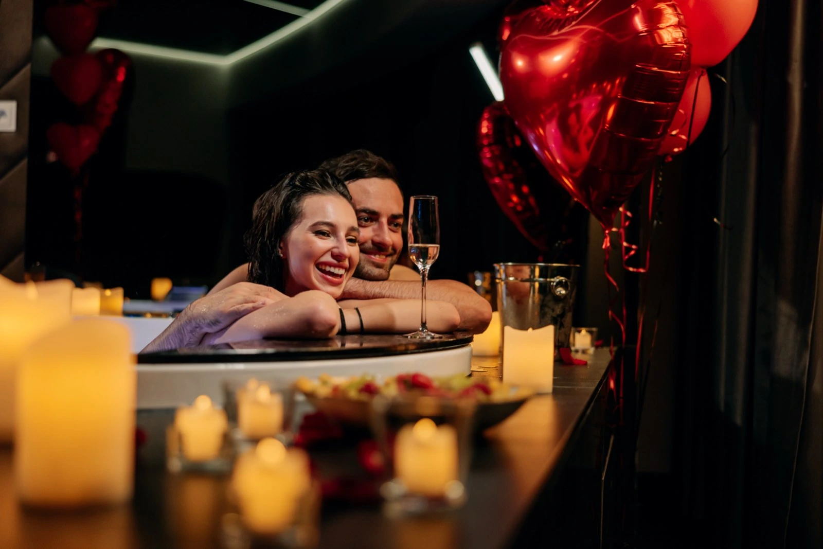 Para w jacuzzi wśród balonów w kształcie serc