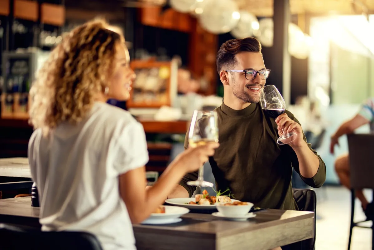 Para przy kolacji w restauracji, kieliszki wina w dłoniach